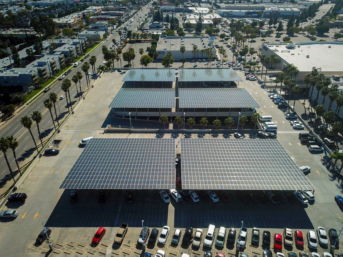 Aerial view of a retail center with solar canopies over its parking field