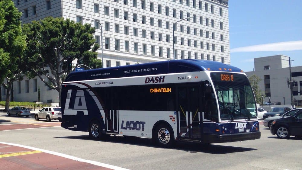 A transit bus at a downtown facility with solar carports overhead
