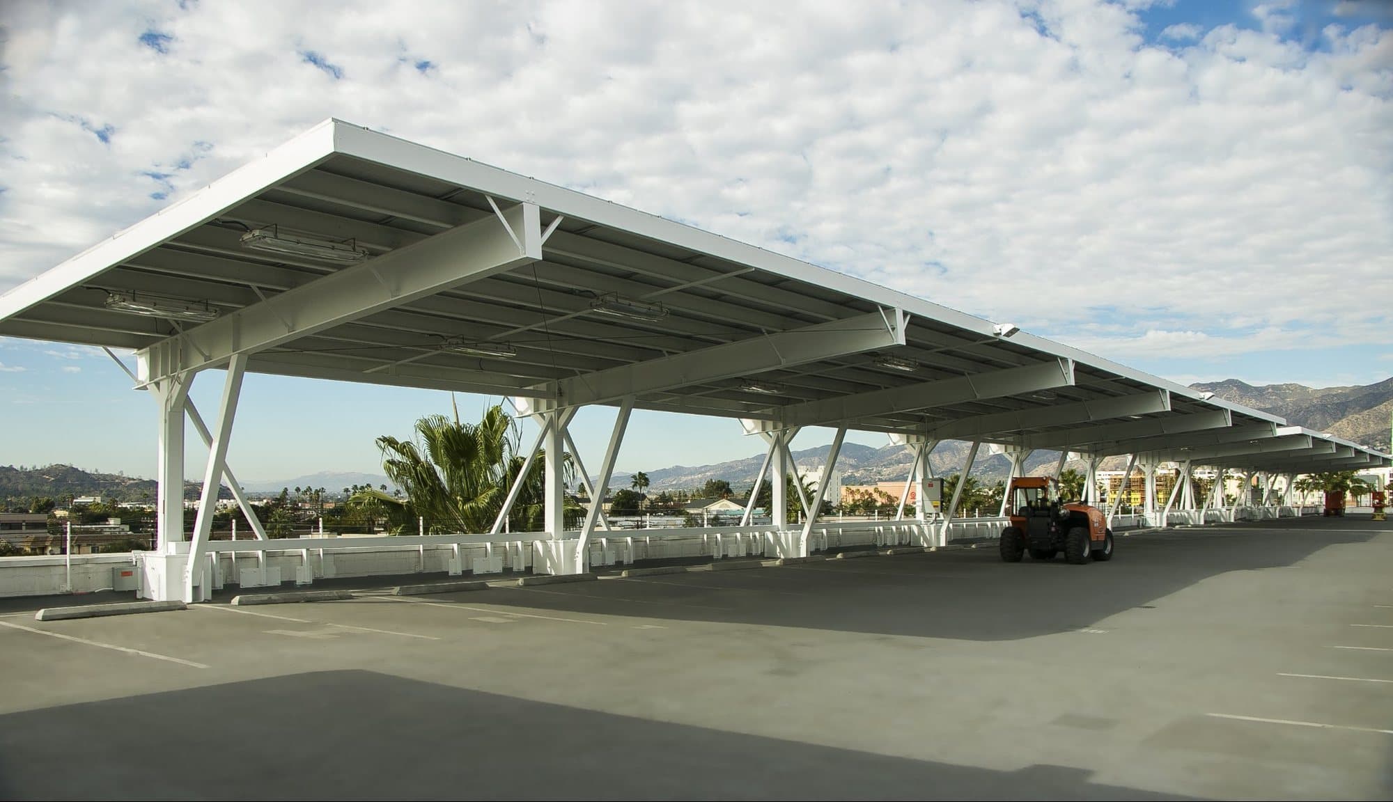 Single-row solar carport with hills behind it on a sunny day