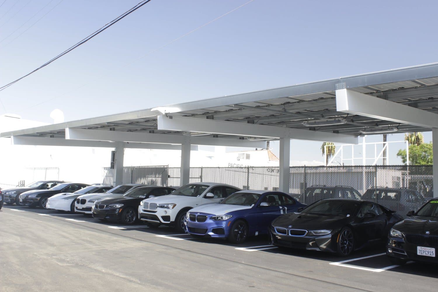 Double-row solar carport over a dealership lot with vehicles parked underneath